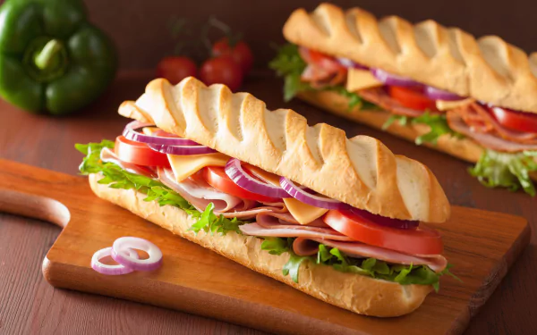 HD wallpaper featuring delicious sandwiches with fresh vegetables, cheese, and meat on crispy bread, set on a wooden board. Tags: bread, food, sandwich.