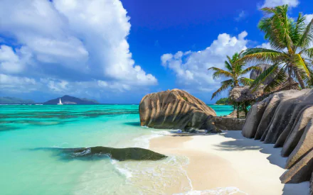 Tropical Seychelles beach with palm trees, crystal-clear turquoise ocean, smooth granite boulders, and a bright blue sky, captured in stunning HD for a desktop wallpaper.