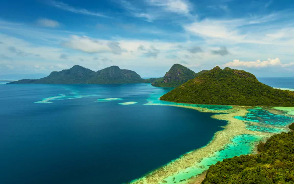 Aerial view of Dulang Island, Malaysia, surrounded by turquoise ocean waters and lush greenery under a bright blue sky, showcasing stunning natural beauty.
