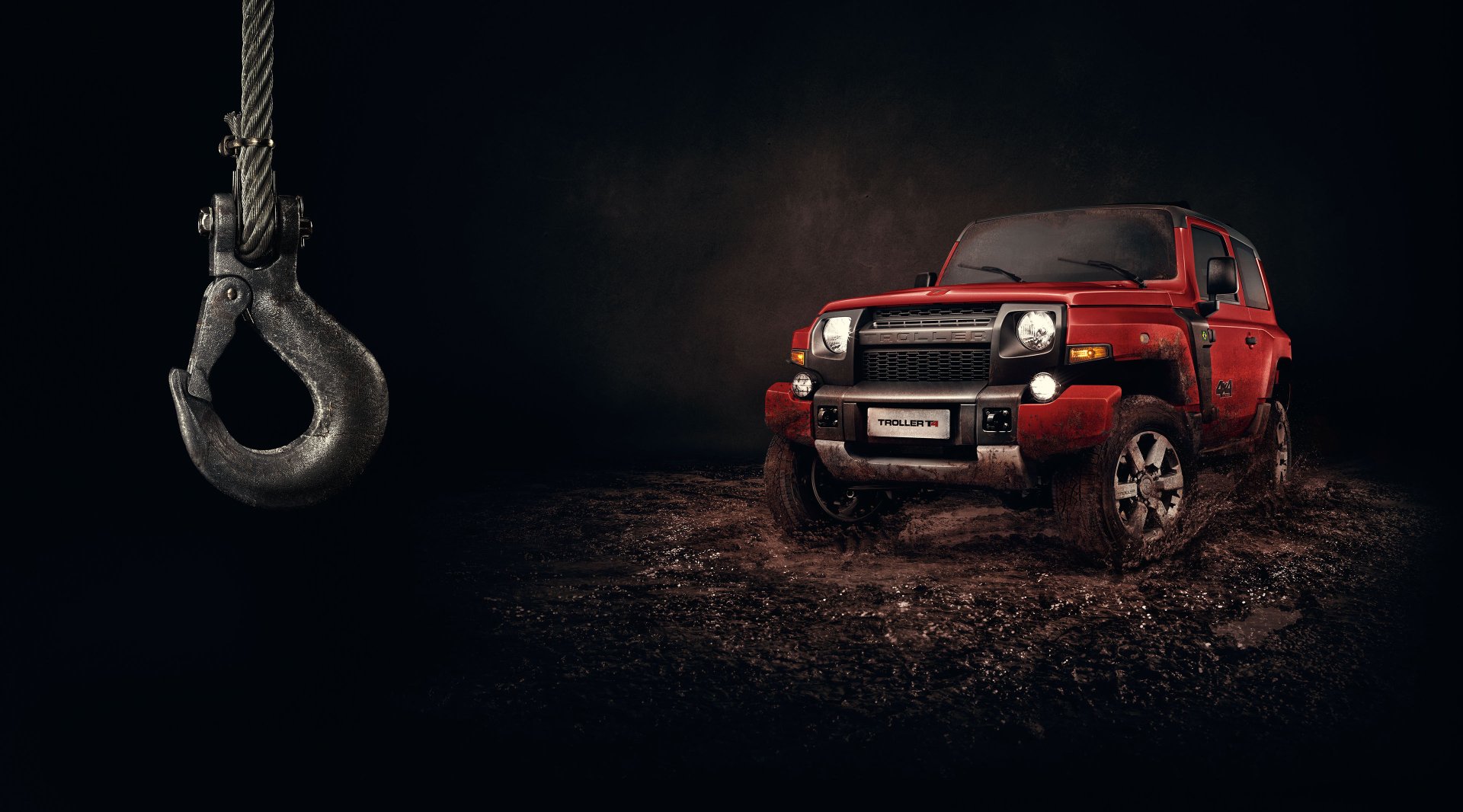 Red Troller T4 off-road vehicle on muddy terrain under a dramatic dark sky with a dangling metal hook, 2K Quad HD PC desktop wallpaper and background.