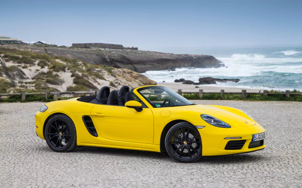 Yellow Porsche Boxster convertible parked by a coastal road; 4K Ultra HD PC desktop wallpaper/background.