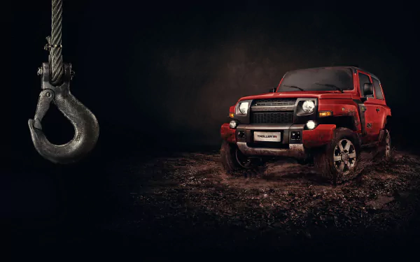 Red Troller T4 off-road vehicle on muddy terrain under a dramatic dark sky with a dangling metal hook, 2K Quad HD PC desktop wallpaper and background.