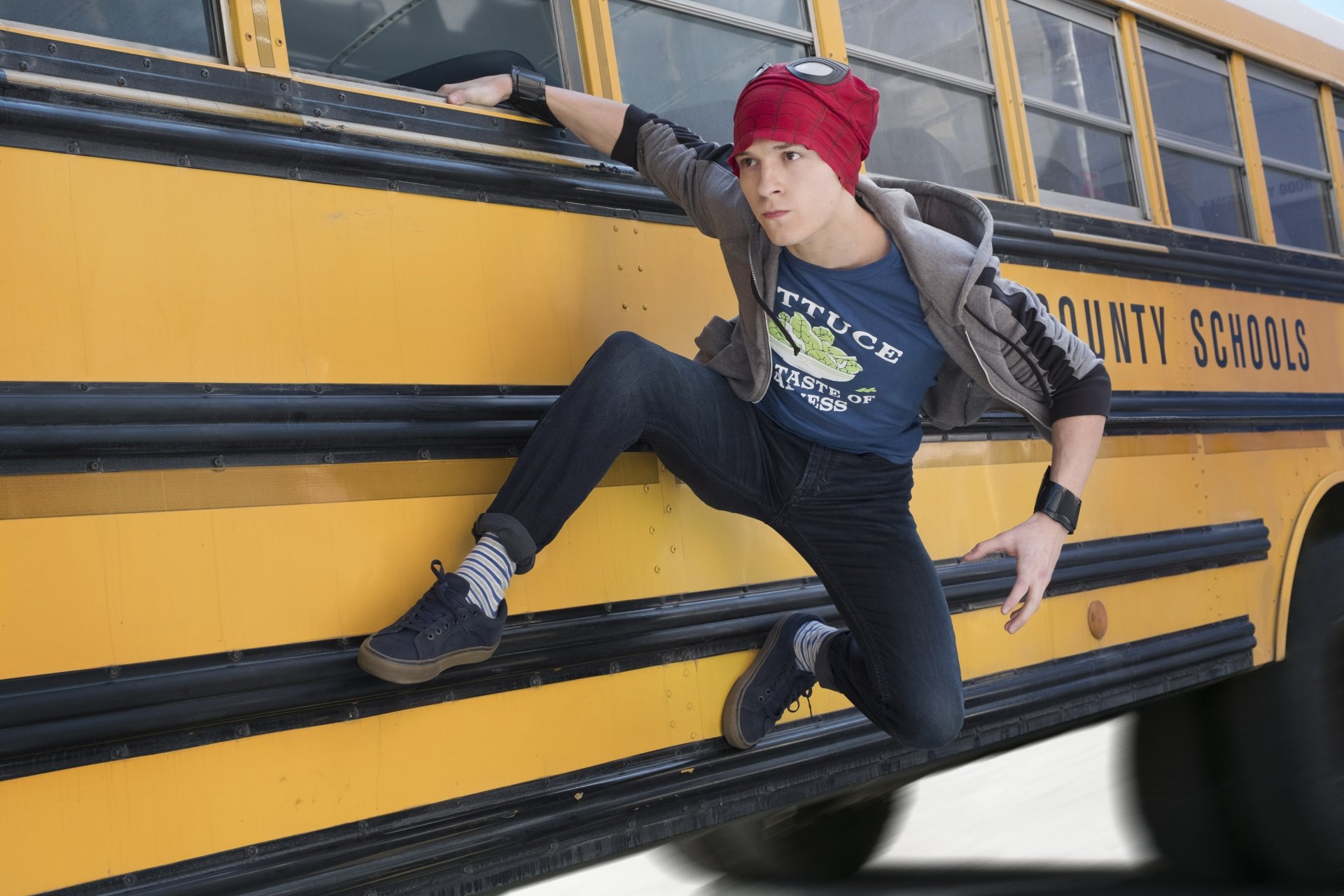Tom Holland as Spider-Man clinging to the side of a school bus, from the movie Avengers: Infinity War. HD desktop wallpaper and background image.