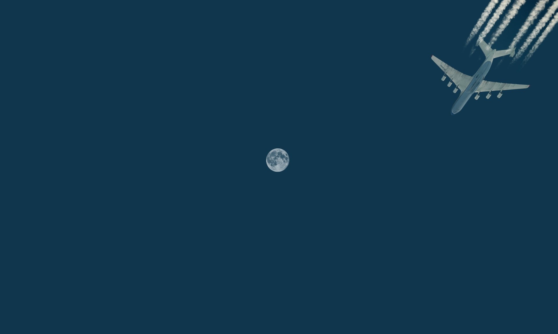 4K Ultra HD wallpaper showing a passenger plane flying across a deep blue sky with the moon visible in the background.