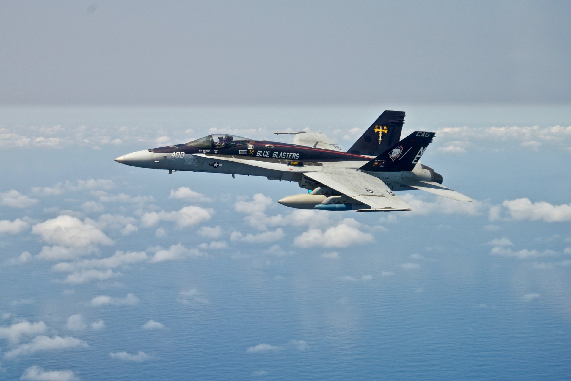 A McDonnell Douglas F/A-18 Hornet military jet fighter flies above the clouds in a clear sky, showcased as an HD PC desktop wallpaper and background.