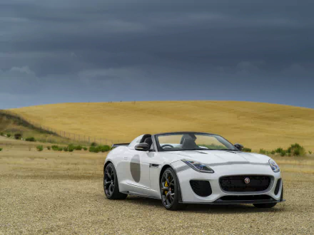 White Jaguar F-Type convertible on a gravel plain with rolling golden hills under a dramatic sky — 5K Ultra HD PC desktop wallpaper and background of the sports car.