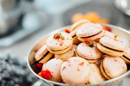 Close-up of pale pink macarons with pistachio and rose garnish in a bowl — biscuit dessert food, 4K Ultra HD PC desktop wallpaper and background.