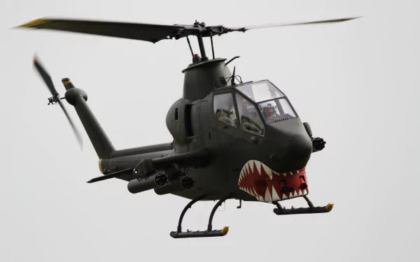 Bell AH-1 Cobra attack helicopter in flight, military aircraft gunship with shark-mouth nose art on a neutral background — HD PC desktop wallpaper/background.