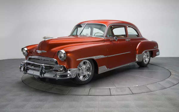 A vibrant red Chevrolet DeLuxe vintage vehicle showcased as a HD PC desktop wallpaper and background with a clean, neutral backdrop.