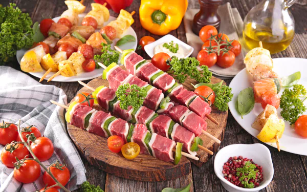 A 4K Ultra HD still life showing raw meat skewers with tomatoes, bell peppers, and herbs arranged for a barbecue feast on a rustic wooden table.