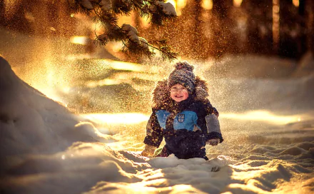 Little boy in a furry hat laughing in deep winter snow, warm golden backlight and shallow depth of field — winter photography HD PC desktop wallpaper and background.