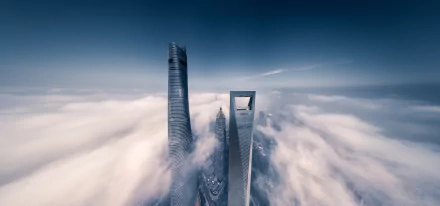 Aerial view of towering skyscrapers piercing through fog over Shanghai’s horizon, showcasing the city’s modern man-made skyline in China.