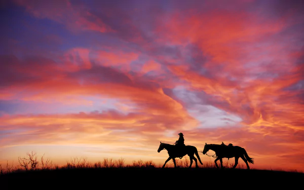 Silhouette of a cowboy riding a horse against a vibrant sunset sky with dramatic clouds. HD desktop wallpaper and background featuring sky, cloud, silhouette, horse, and sunset photography.