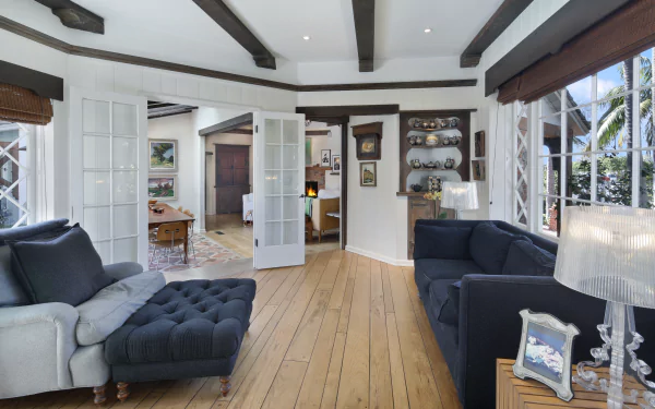 A bright living room with wooden floors, exposed ceiling beams, and modern sofas arranged around a cozy, inviting space, captured in 4K Ultra HD quality.