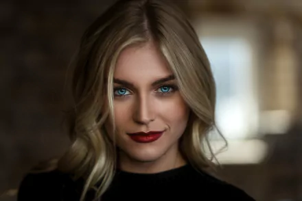 HD desktop wallpaper of a smiling blonde woman with blue eyes wearing red lipstick, captured in a close-up portrait against a softly blurred background.