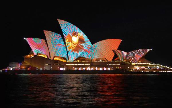 The Sydney Opera House in Australia illuminated with colorful, vibrant light projections against a night sky, showcased as a stunning HD desktop wallpaper background.