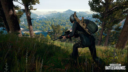 A high-definition desktop wallpaper of Playerunknown's Battlegrounds showing an armed player character in a forested landscape, ready for action. The game logo is visible in the bottom right corner.