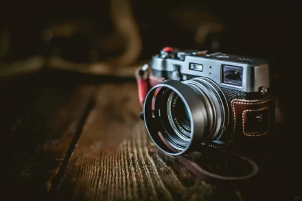 HD PC desktop wallpaper featuring a Fujifilm man-made camera resting on a wooden surface with a blurred background.