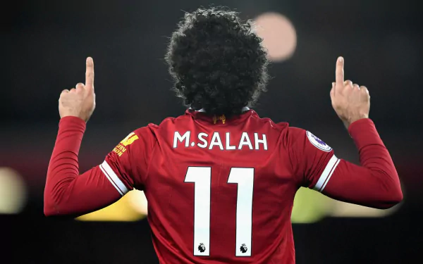 HD PC desktop wallpaper featuring Mohamed Salah in his red sports jersey, number 11, celebrating with both index fingers pointed upward.