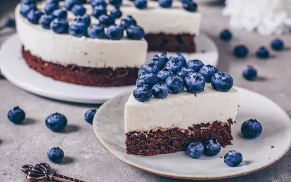 A slice of blueberry cheesecake with fresh berries on top, set against a gray background, showcased as an HD PC desktop wallpaper and background.