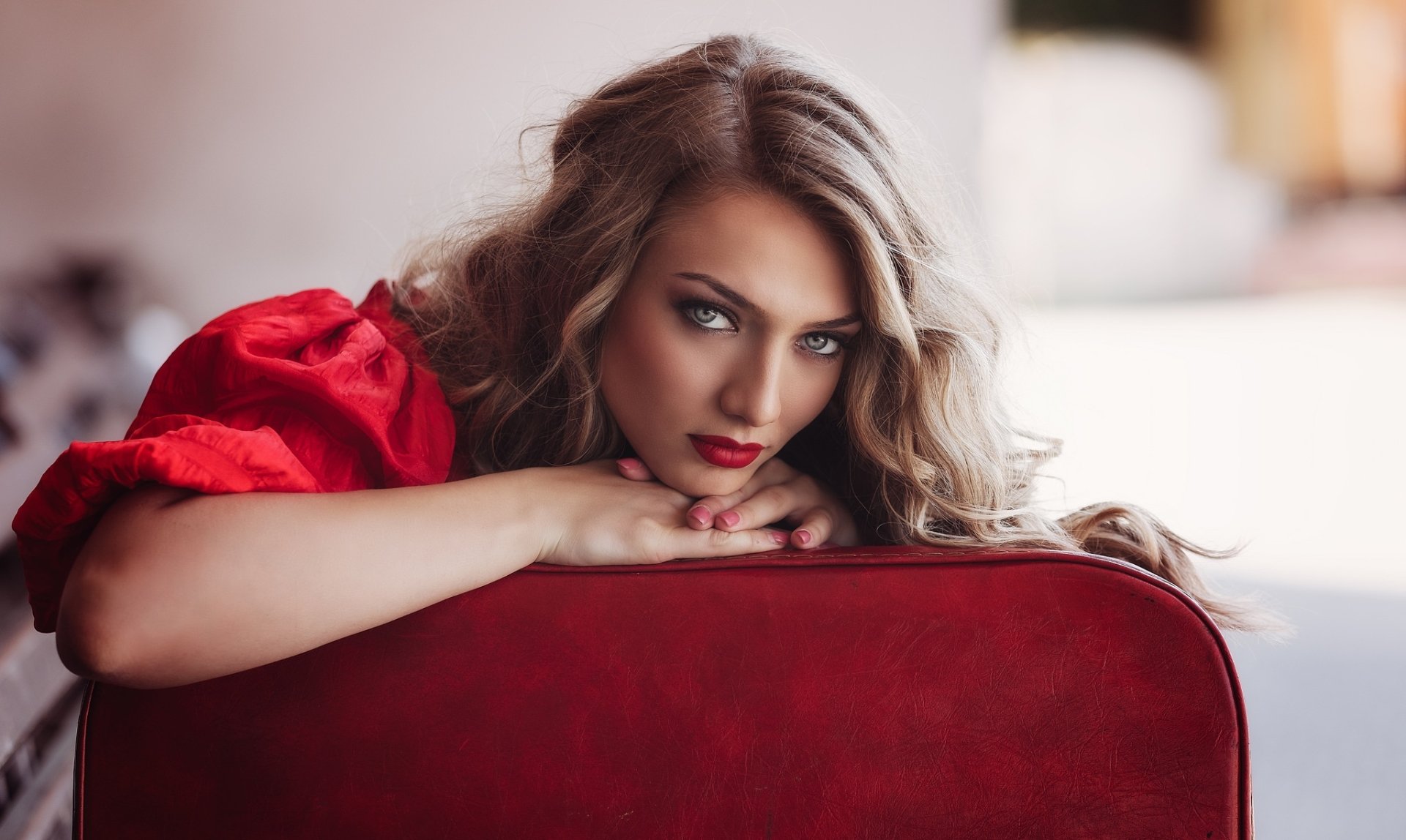 HD desktop wallpaper featuring a blonde woman with blue eyes and bold lipstick, captured with a shallow depth of field for a striking, soft-focused portrait.