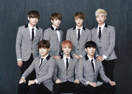 A high-definition desktop wallpaper featuring the popular South Korean music group BTS, showcasing all seven members in stylish gray suits against a dark backdrop.