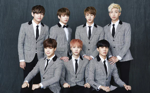 A high-definition desktop wallpaper featuring the popular South Korean music group BTS, showcasing all seven members in stylish gray suits against a dark backdrop.