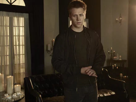 2K Quad HD PC desktop wallpaper: lone man in a dim, candlelit room with leather sofa and tall windows — Cloak & Dagger TV show background.