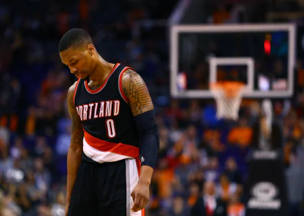 HD wallpaper of Damian Lillard in a Portland Trail Blazers jersey on the basketball court, looking down thoughtfully.