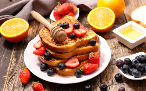 8K Ultra HD PC desktop wallpaper: still-life breakfast of stacked toast topped with strawberries, blueberries and honey, with orange halves and a honey dish on a rustic wooden table.