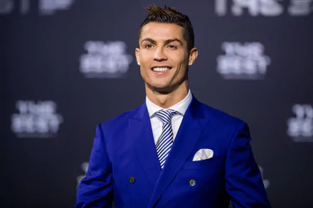 HD desktop wallpaper featuring Portuguese soccer star Cristiano Ronaldo, dressed in a stylish blue suit, smiling against a dark background. Tags: Portuguese, soccer, Cristiano Ronaldo, sports.