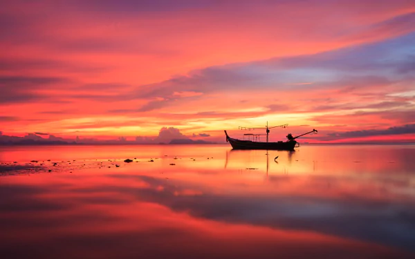A fishing boat reflects on calm waters under a vibrant sunset sky on the horizon, captured in stunning 4K Ultra HD.