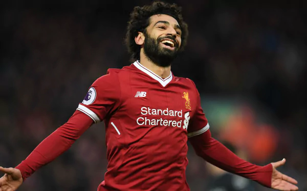 Smiling soccer player in a red Liverpool kit celebrating on the pitch — dynamic 4K Ultra HD PC desktop sports wallpaper