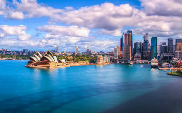 Sydney Harbour and Circular Quay feature the iconic Sydney Opera House and city skyscrapers under a partly cloudy sky in this HD desktop wallpaper.