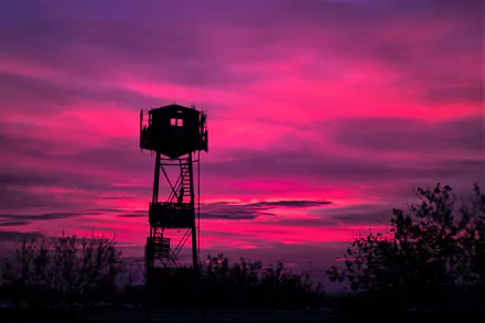Silhouette of a watchtower against a vibrant pink sunset sky, captured in stunning HD photography, creating a striking desktop wallpaper and background.