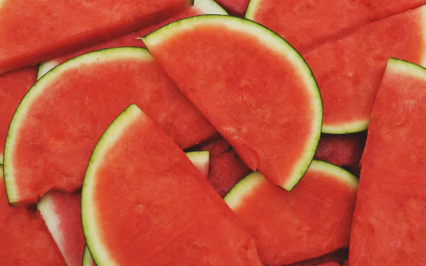 Close-up view of fresh watermelon slices with vibrant red flesh and green rind, presented as a vivid 4K Ultra HD desktop wallpaper and background.