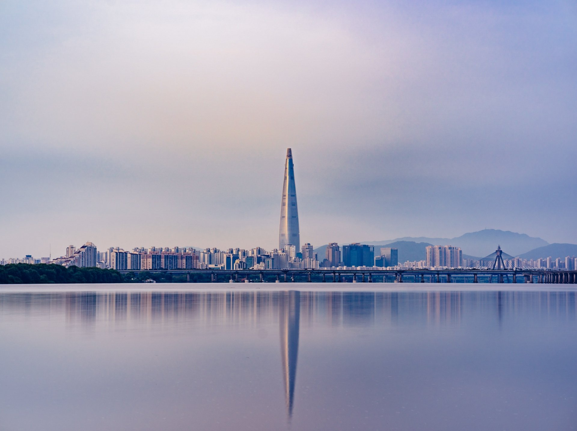 4K Ultra HD wallpaper of Seoul’s skyline featuring the Lotte World Tower skyscraper reflected in calm waters, showcasing modern city architecture in South Korea.