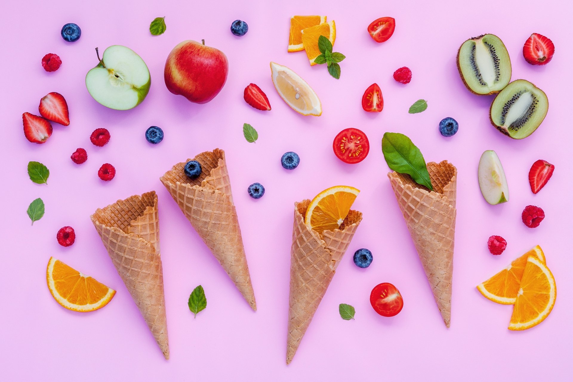 5K Ultra HD PC desktop wallpaper: still-life food arrangement of empty waffle cones and scattered fruit—strawberries, blueberries, kiwi, apple and orange—on a pink background.