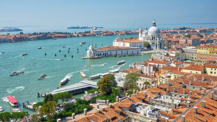 HD desktop wallpaper of Venice, Italy showcasing the city's iconic buildings, numerous boats on the water, and stunning architectural details against a clear blue sky.