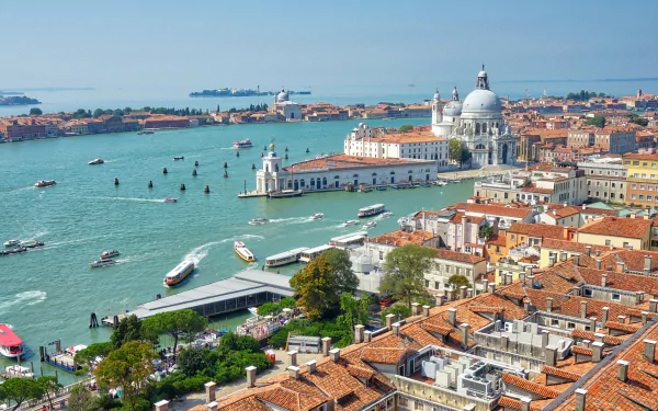 HD desktop wallpaper of Venice, Italy showcasing the city's iconic buildings, numerous boats on the water, and stunning architectural details against a clear blue sky.
