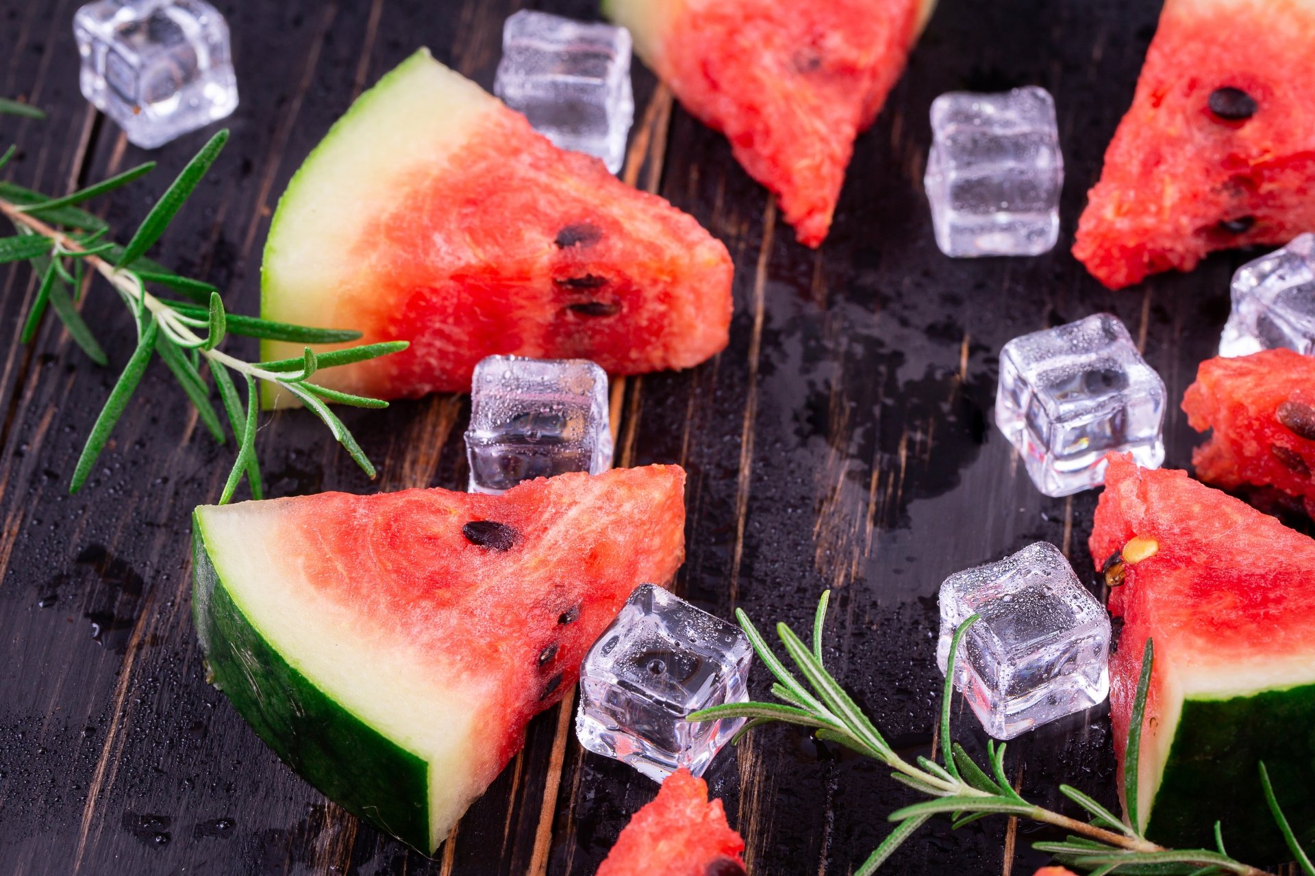 5K Ultra HD PC desktop wallpaper: watermelon wedges and ice cubes on a dark board, garnished with herb sprigs and glistening water droplets.