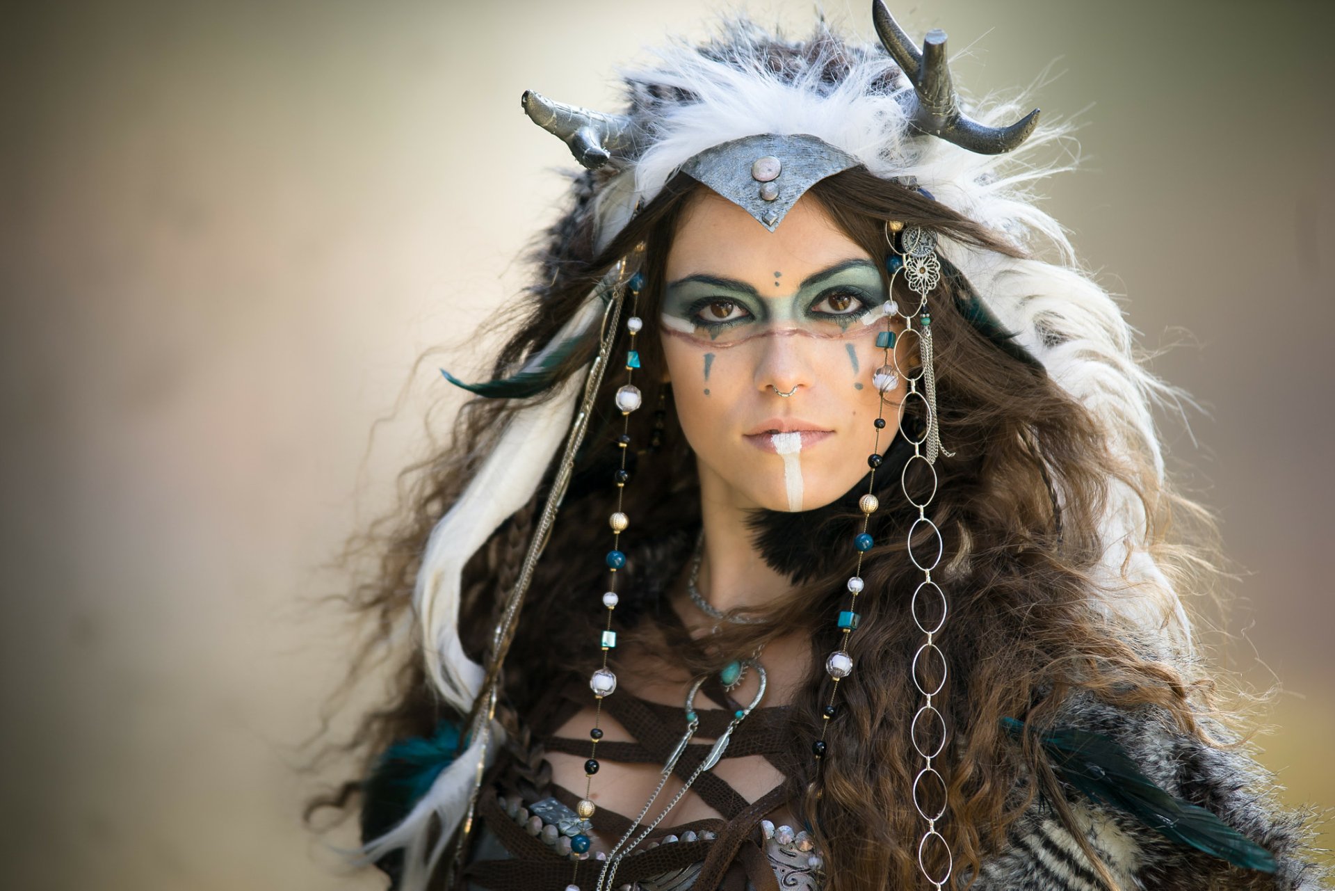 HD desktop wallpaper featuring a brunette woman with brown eyes in detailed cosplay makeup and adorned with antler-like headpiece and beads.