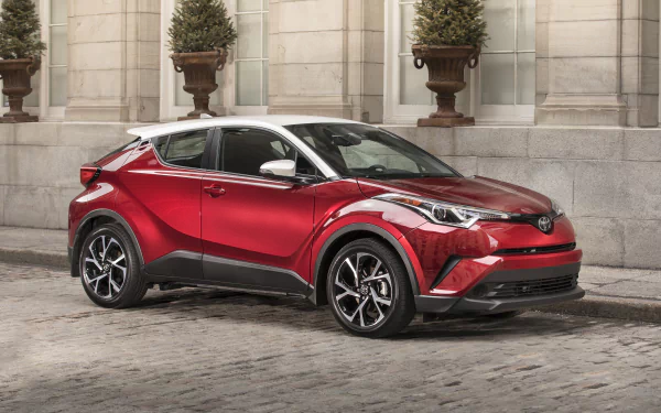 Red Toyota C-HR compact SUV car on a cobblestone street, 4K Ultra HD PC desktop wallpaper and background showcasing the vehicle's bold angular crossover design.
