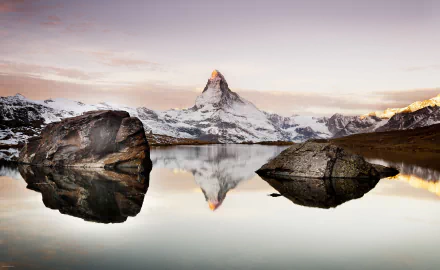 HD desktop wallpaper featuring a stunning reflection of the Matterhorn in a tranquil alpine lake. The serene nature scene showcases the majestic Alps, perfectly mirrored on the calm water.