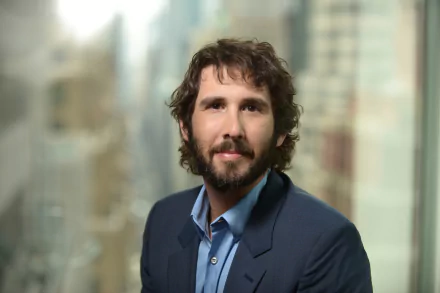 A high-definition desktop wallpaper featuring Josh Groban, showcasing the singer with a city backdrop, exuding confidence and charm.