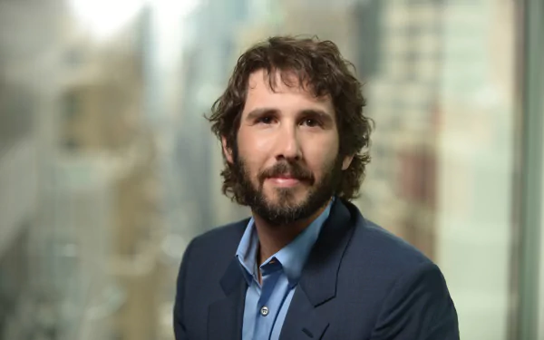 A high-definition desktop wallpaper featuring Josh Groban, showcasing the singer with a city backdrop, exuding confidence and charm.