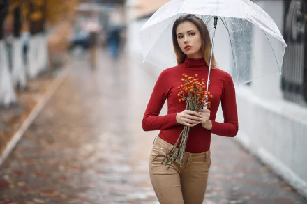 Brunette model with brown eyes and red lipstick holds a clear umbrella and small bouquet on a rainy street; shallow depth-of-field, 2K Quad HD PC desktop wallpaper/background.