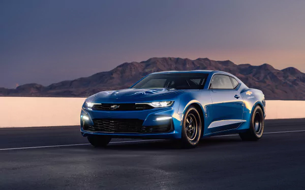 Blue Chevrolet Camaro on an open desert road at dusk with distant mountains — 4K Ultra HD PC desktop wallpaper and background.