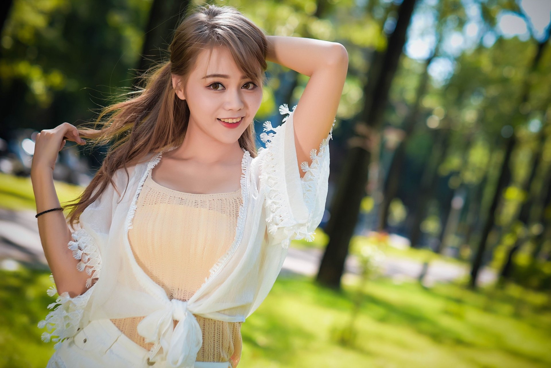 Asian woman with long hair smiles brightly in a sunlit outdoor setting, captured with a shallow depth of field, creating a vibrant and warm HD desktop wallpaper.