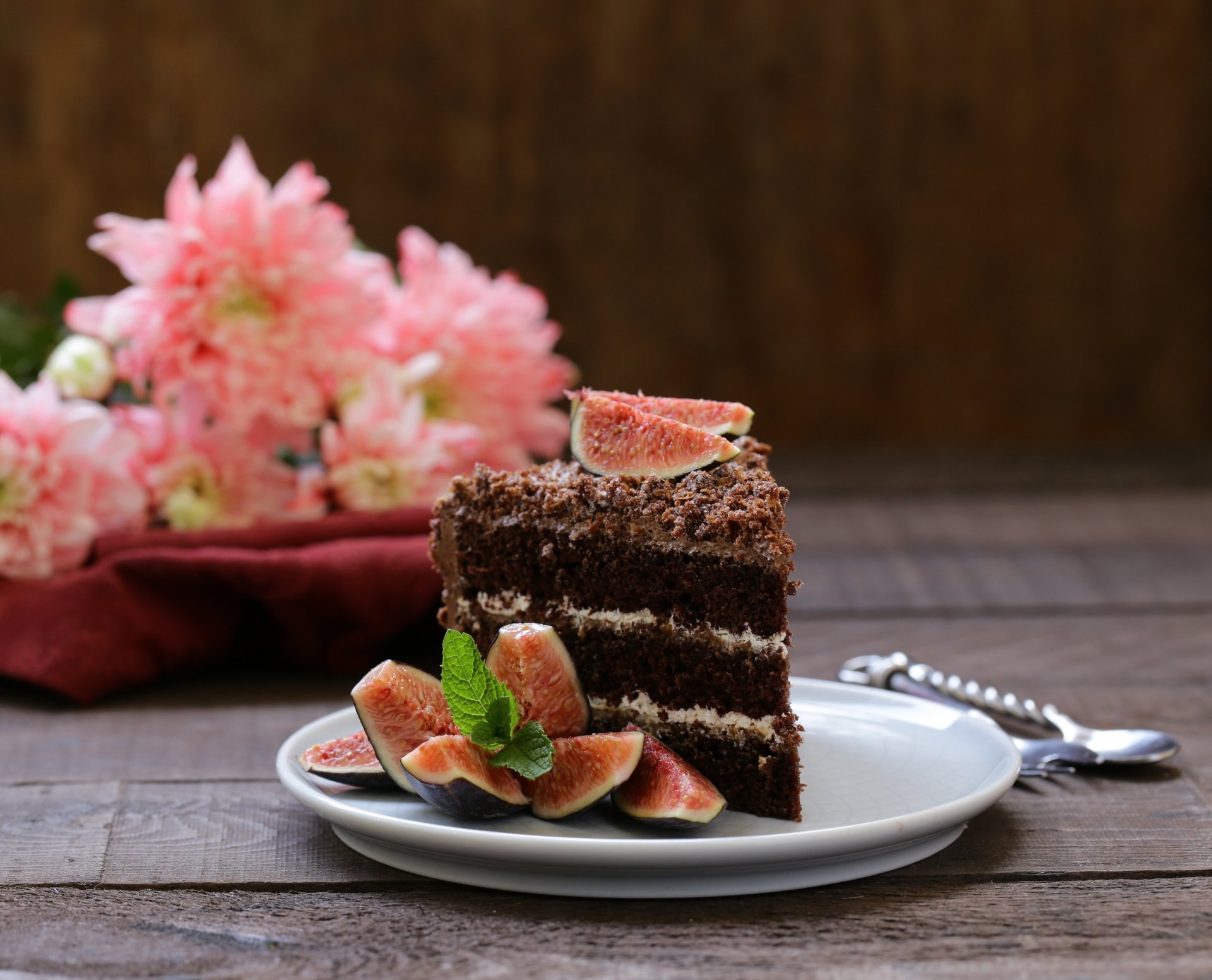 A rich fig-topped chocolate pastry cake dessert on a plate, styled with fresh figs and mint, set against a dark wooden background in 4K Ultra HD quality.